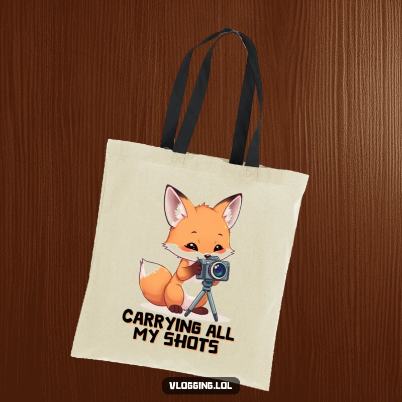 Funny tote bag illustrated with a curious fox intently playing with a miniature camera on a stand, perfect for carrying daily essentials.